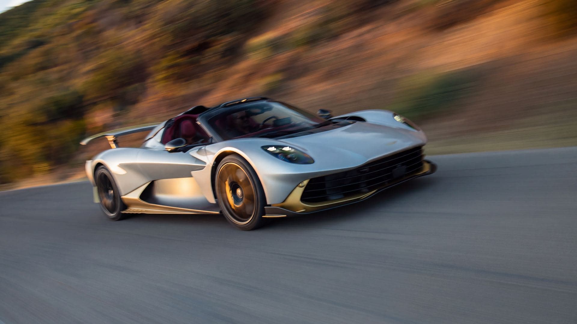 aston martin valhalla spider argent et or toit retire sur une route de colline
