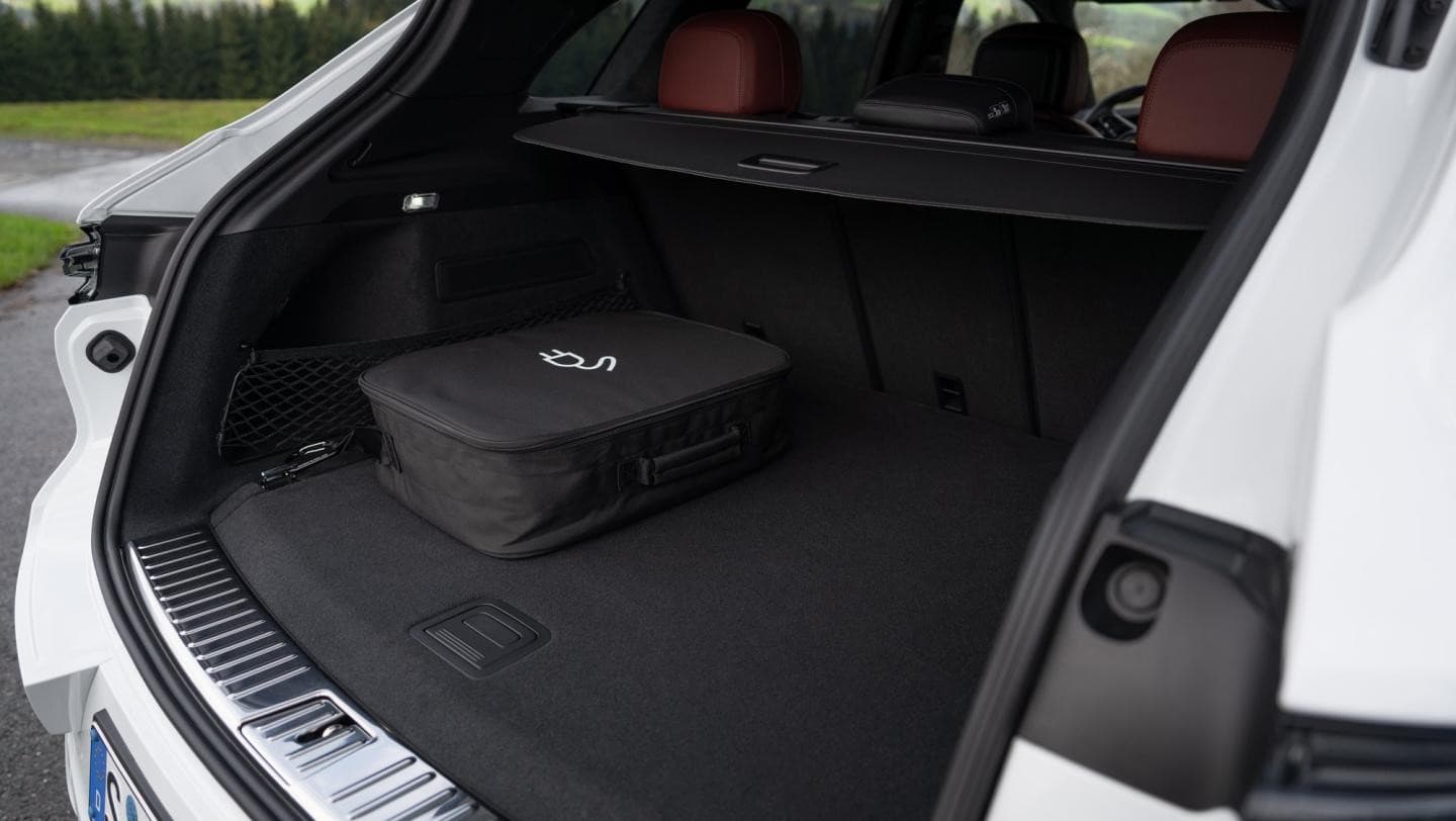 Geöffneter Kofferraum des weißen Porsche Cayenne E-Hybrid mit der Tasche für das Ladekabel