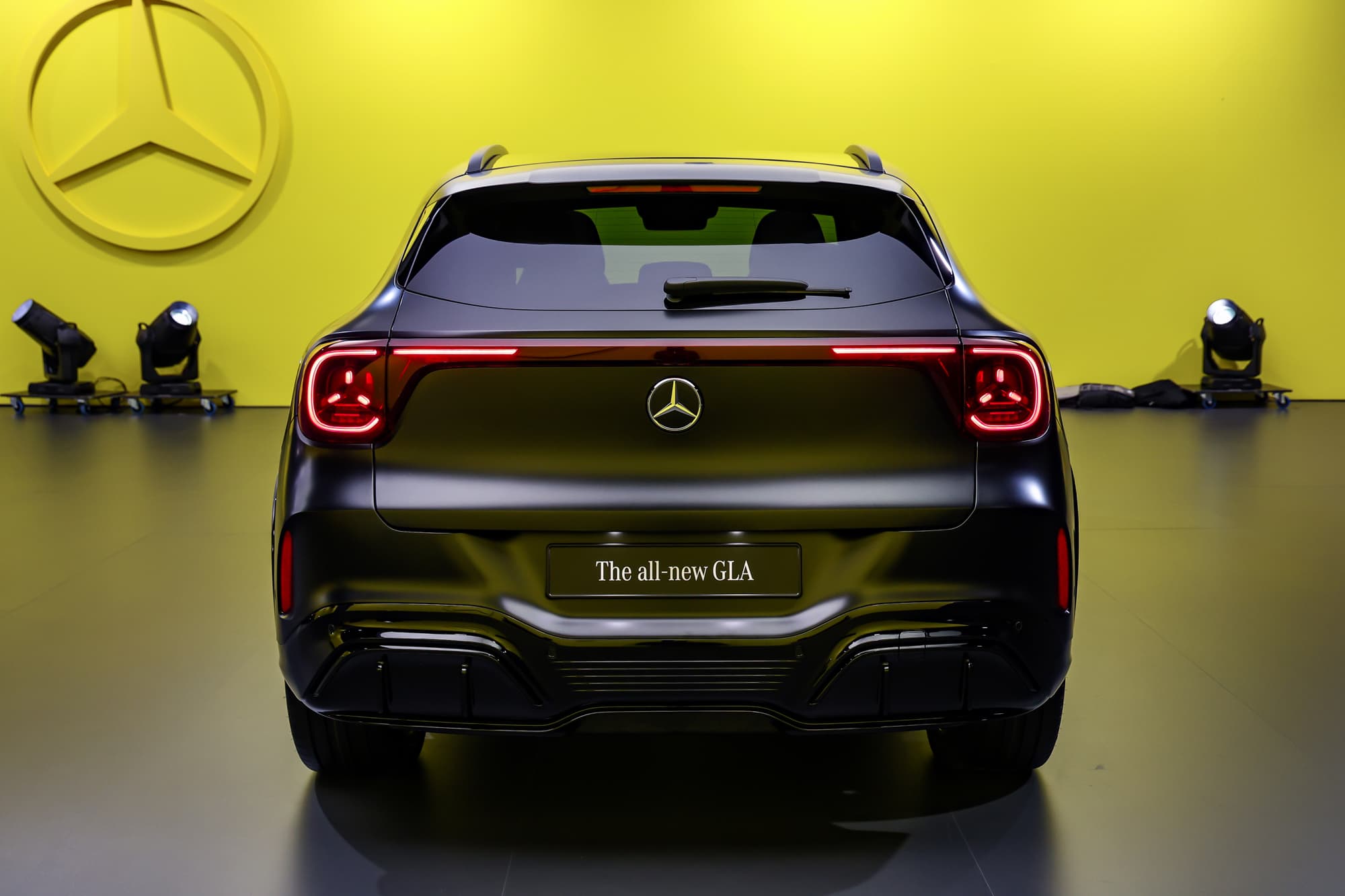 Die neue GLA von hinten auf einer Präsentationsbühne, rotes Leuchtband, gelbe Wand mit Mercedes-Stern